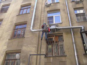 klimmer monteert een ventilatie-unit buiten het gebouw